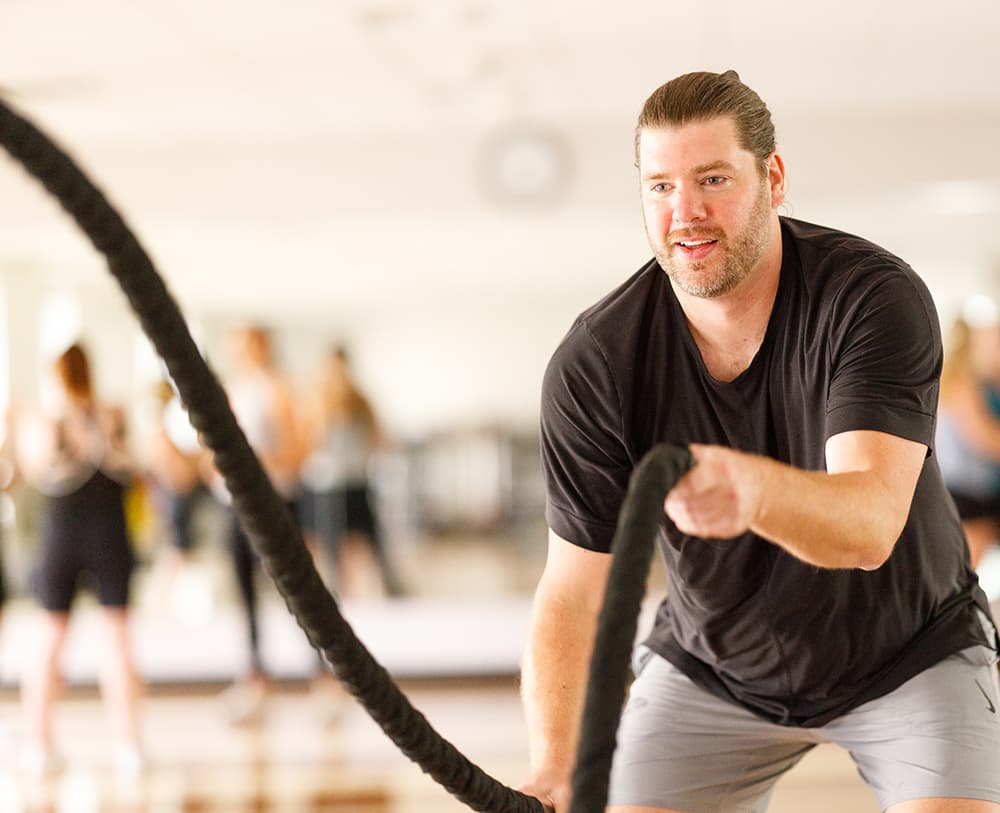 Man does battle rope workout in fitness studio